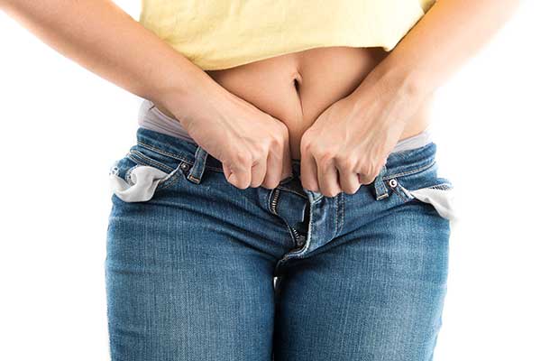 Woman trying to button her pants jeans